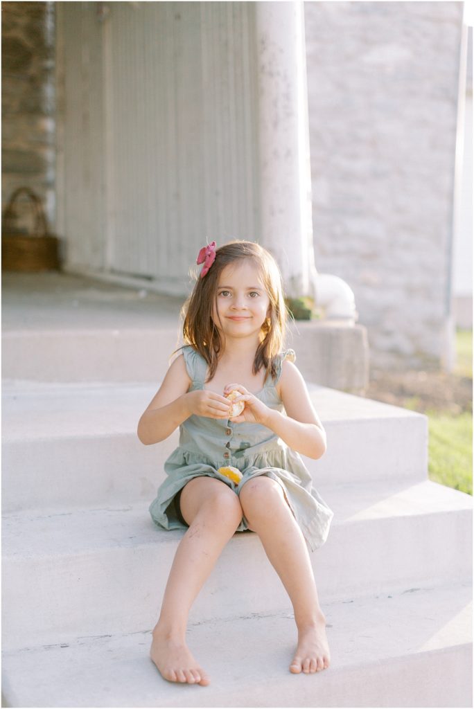 Young girl eating an orange on the porch steps