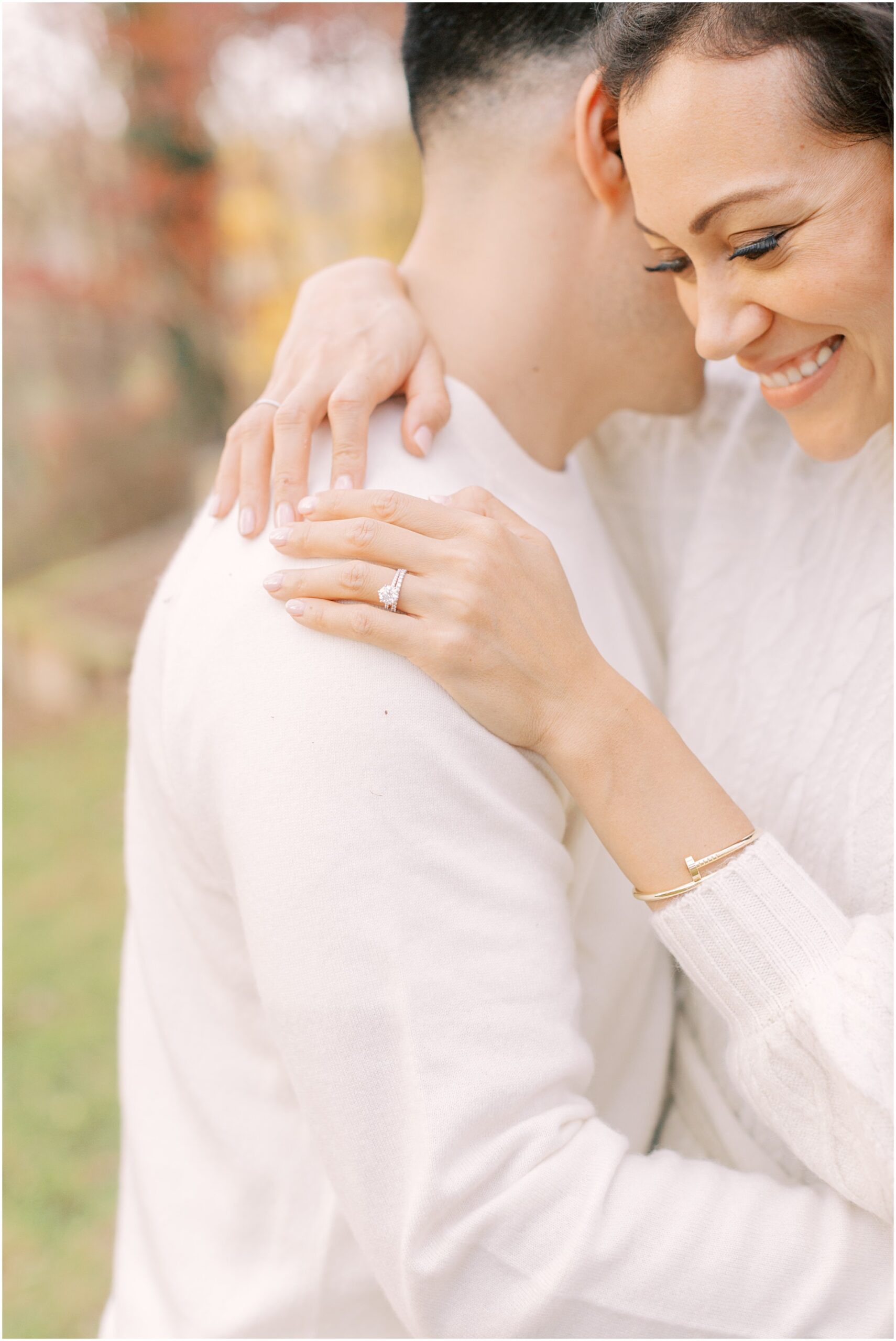 Details of woman hugging her husband with details of her ring at a family photography session. 