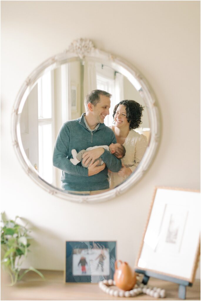 Mirror reflection of parents with a newborn in a Winter Newborn Session Lancaster PA with Angelique Jasmin Photography