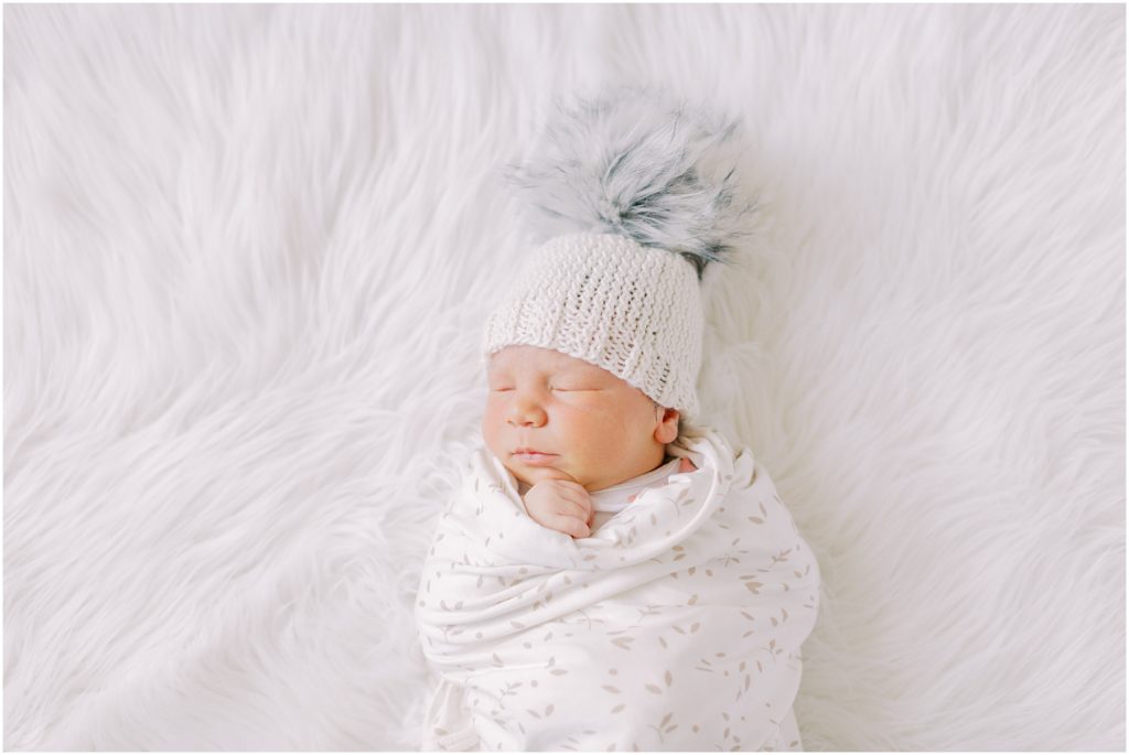 Newborn baby boy with pom pom hat at newborn session at home