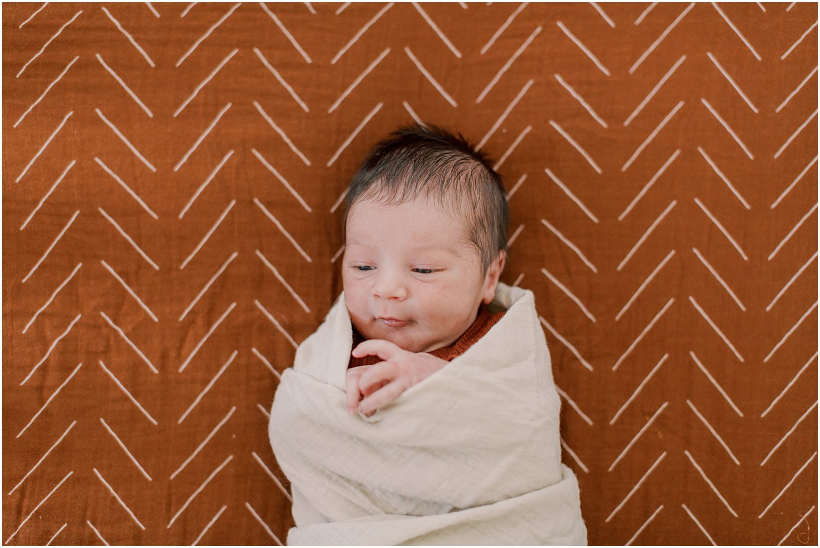 baby boy with rust crib sheet