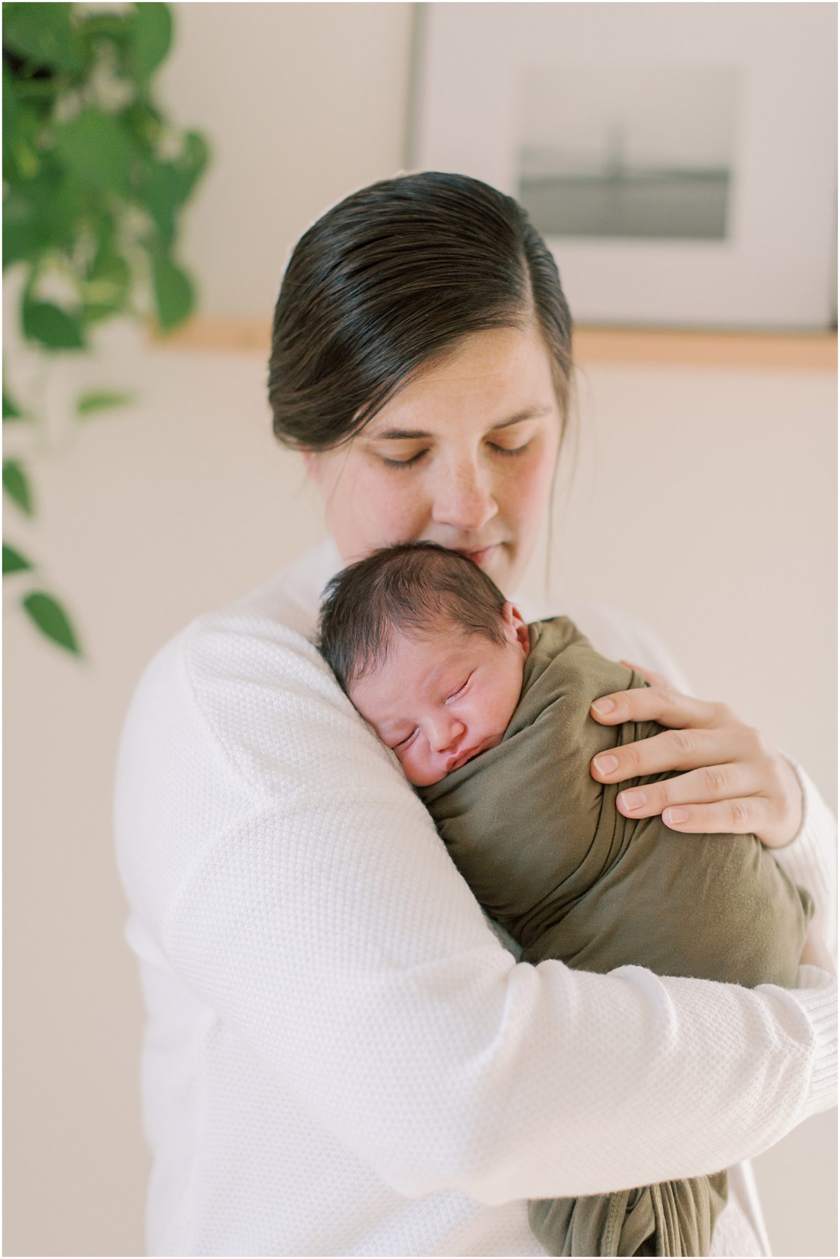 Mother snuggling baby boy in earth toned nursery