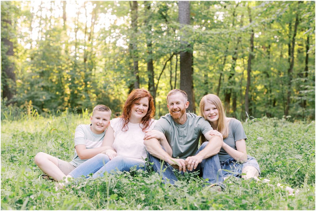 Family sitting together in the woods during a family session with Angelique Jasmin Photography