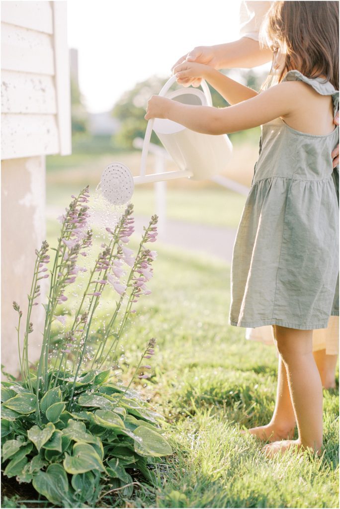 Little Girl watering flowers in slow down, summer