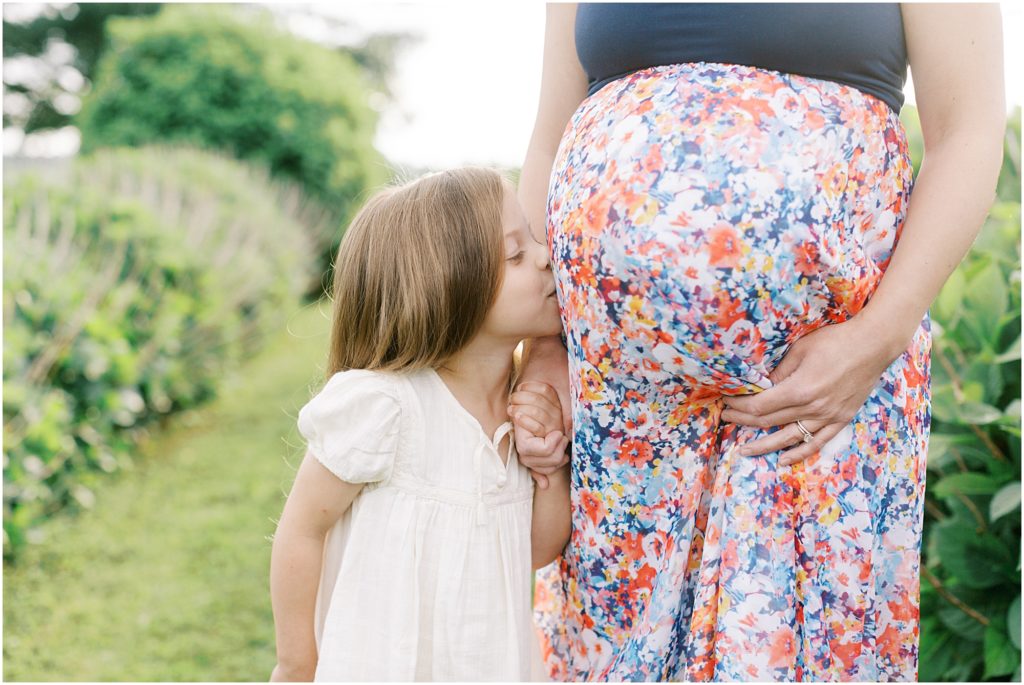 Daughter kissing mother's pregnant belly
