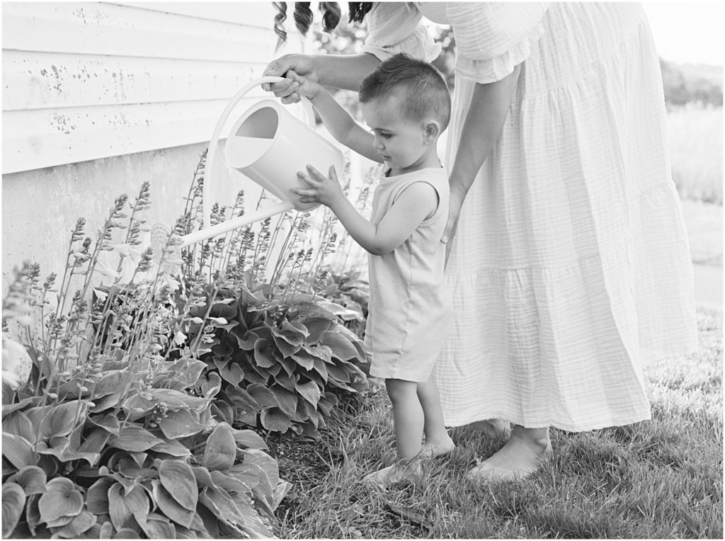 Black and white image of mother watering flowers with her toddler