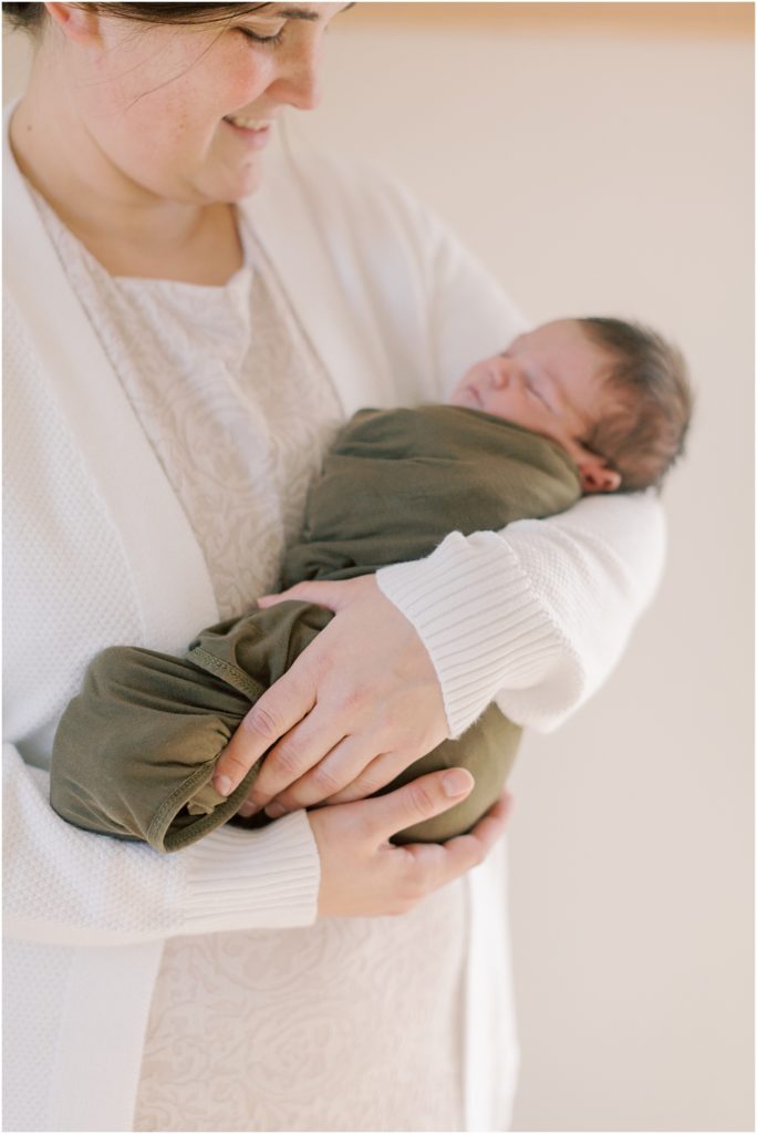Baby in mothers arms in preparing for your newborn session