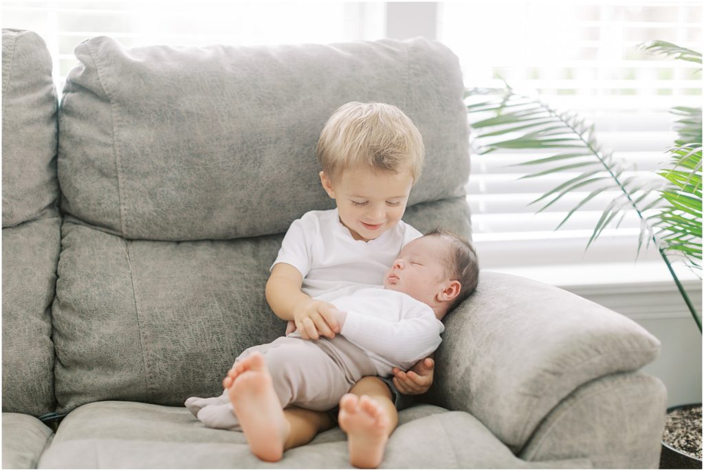 Toddler with baby brother in summer indoor newborn session