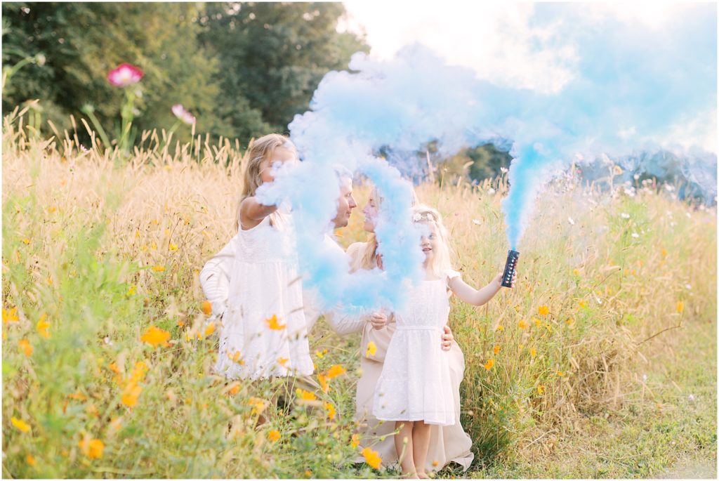 Young girls with smoke bombs at flower field maternity session