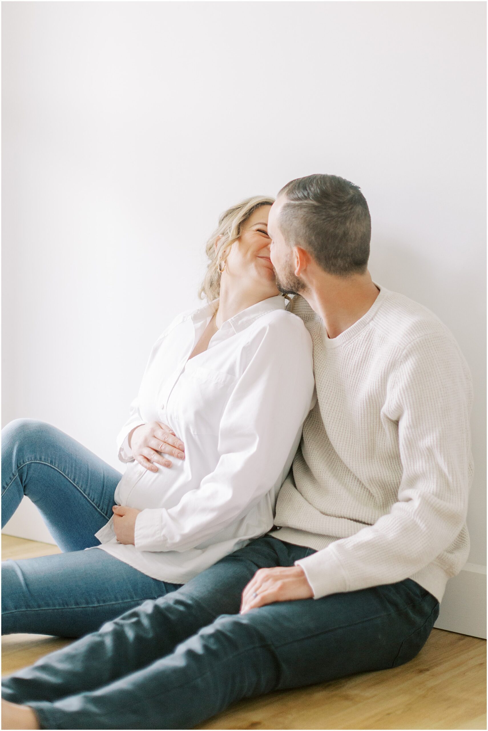 Couple kissing while sitting at indoor maternity session in York PA
