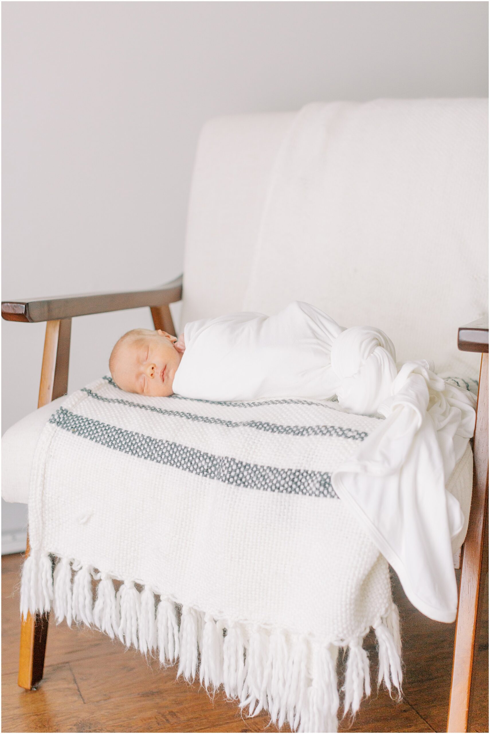 Newborn baby boy in white swaddle lying on a chair