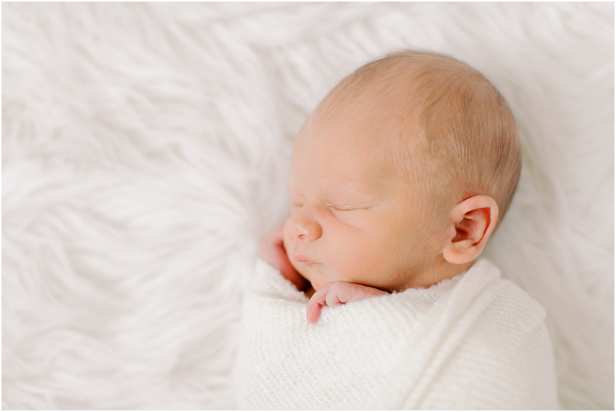 Close up of baby's head with white swaddle and background