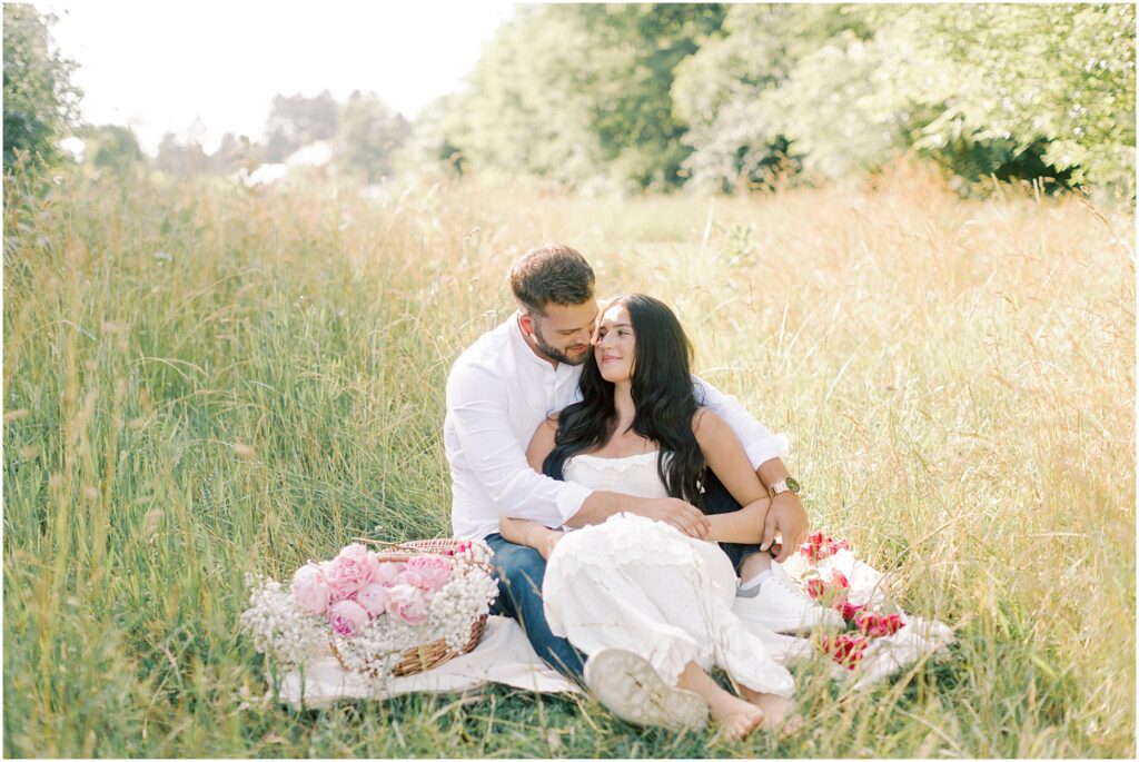 Couple sitting on a blanket with flowers in an intimate maternity session with Angelique Jasmin Photography
