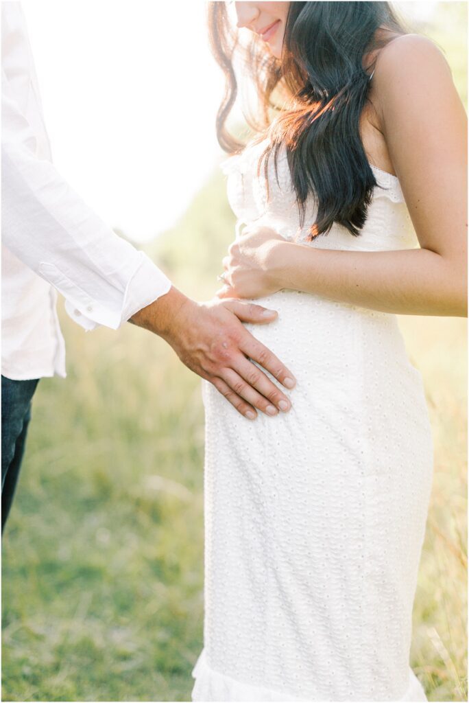 Husband's hand on wife pregnant belly