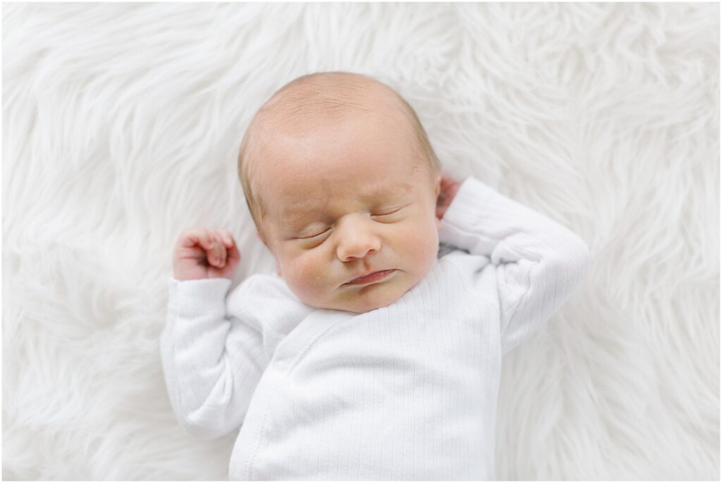 Newborn baby boy on white, fur background.