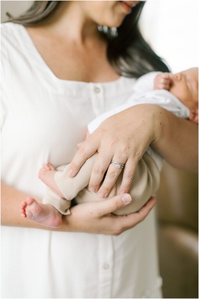 Details of a mother's hands holding her newborn son.