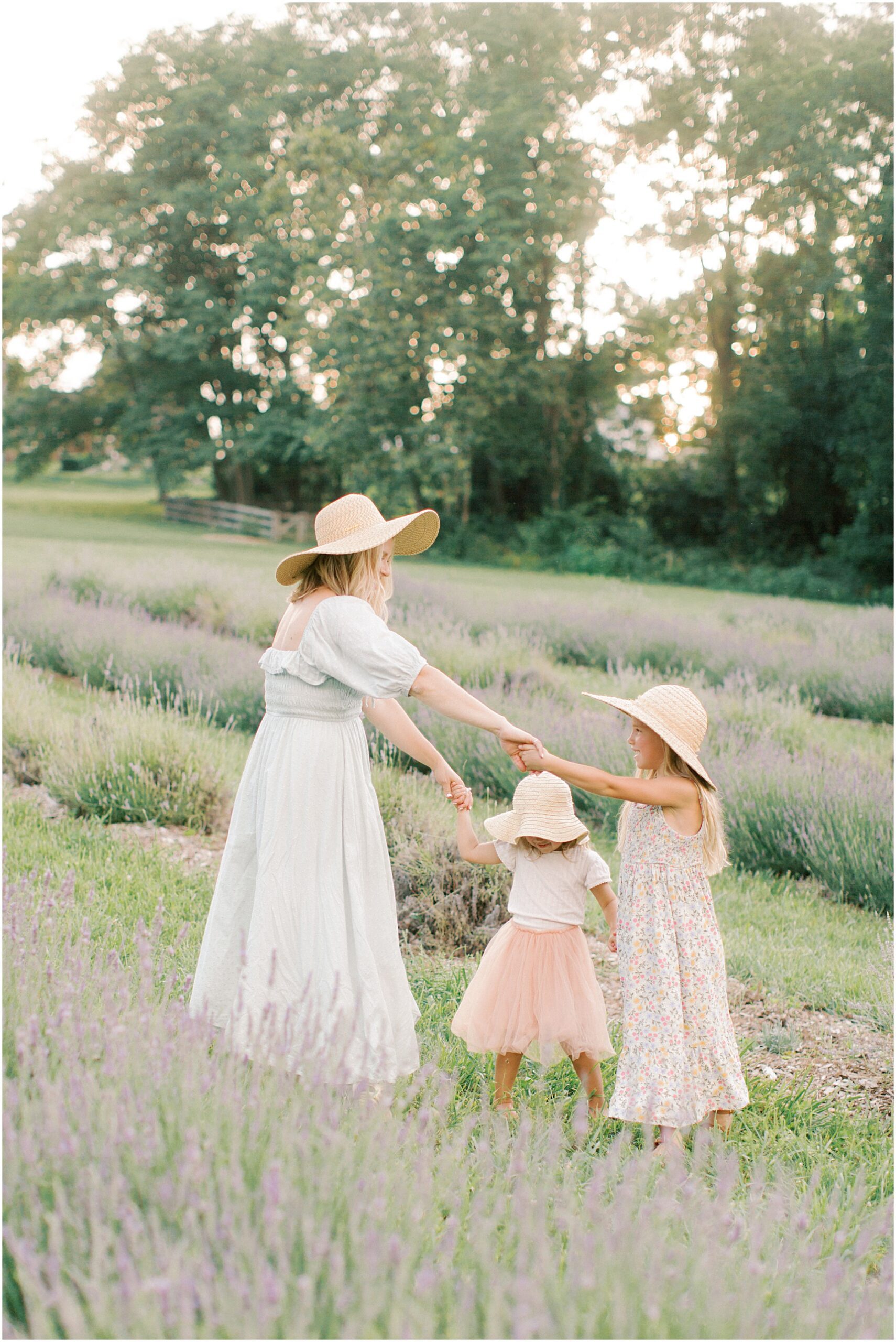 Mother playing Ring Around a Rosy with her girls in a lavender field with Angelique Jasmin Photography