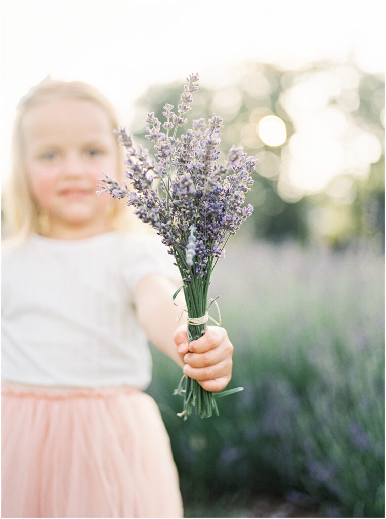 Little girl holding up a lavender bouquet