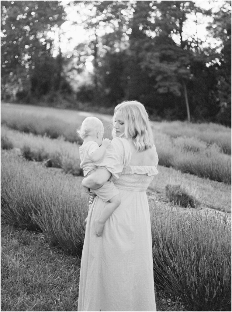 Black and white image of a mother holding her toddler in a lavender field