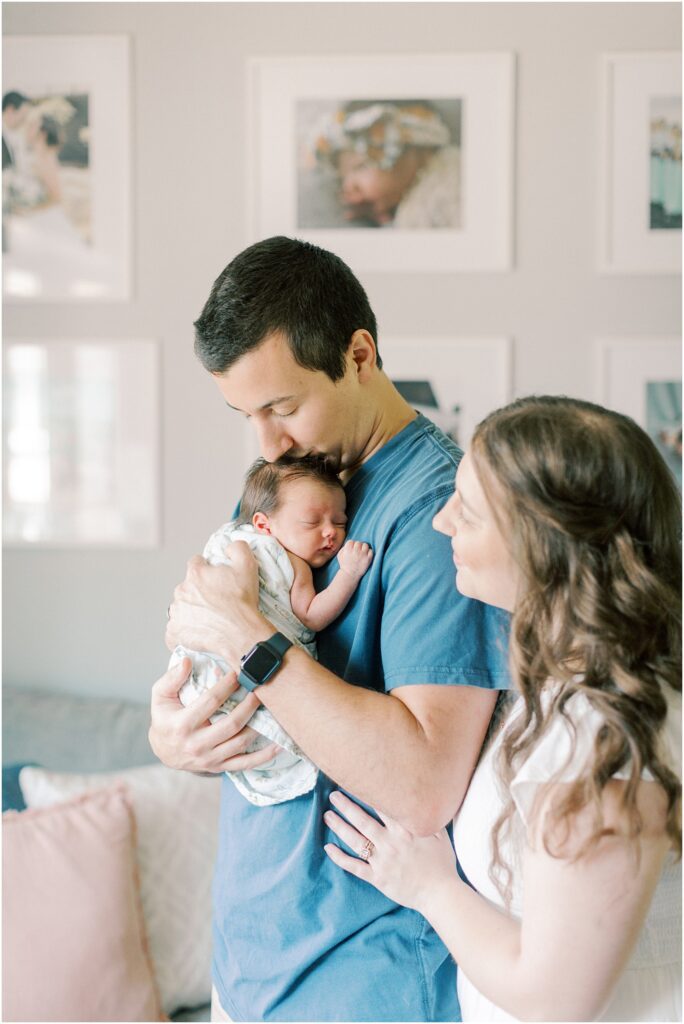 Father kissing his baby daughter's head while wife watches near his shoulder in Elizabethtown PA Newborn Photographer