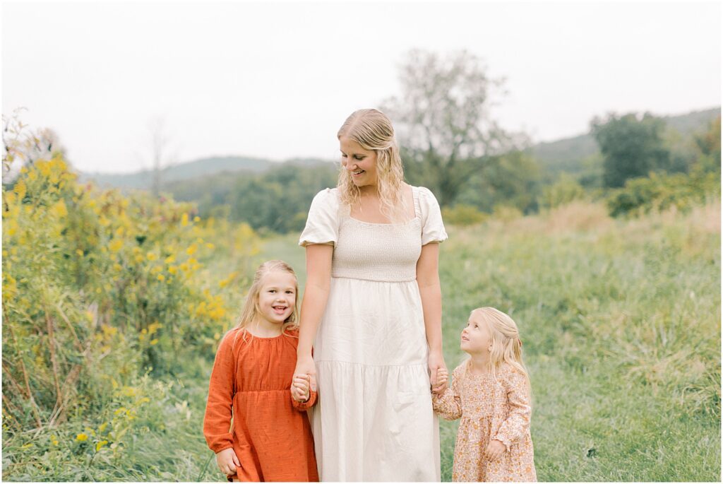 Mother walking with her daughters and looking down at them lovingly at a Lancaster Fall Family Session