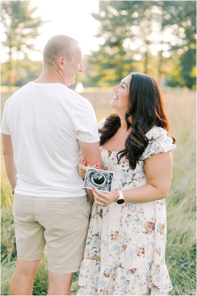 Couple standing together in a field in Lancaster PA Pregnancy Announcement with Angelique Jasmin Photography