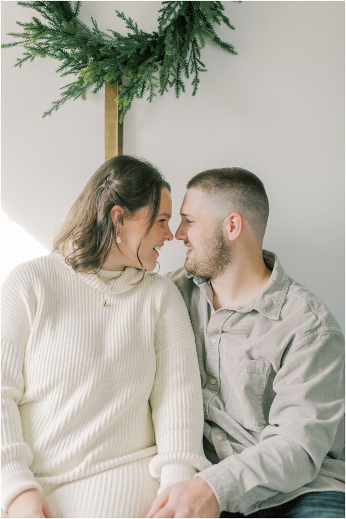 Husband and wife snuggled together nose to nose at a Christmas Mini Session.