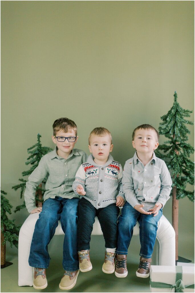 Three little boys sitting together on a bench at Lancaster, PA Christmas Mini Sessions