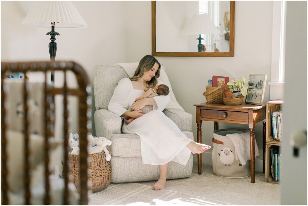 Mother sitting in the nursery holding her newborn son in a lifestyle newborn photography session with Angelique Jasmin Photography