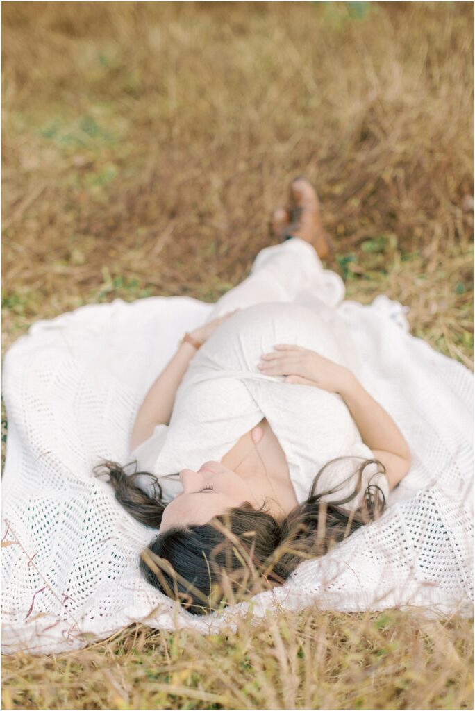 Pregnant mother laying on a blanket in a field of fall grasses