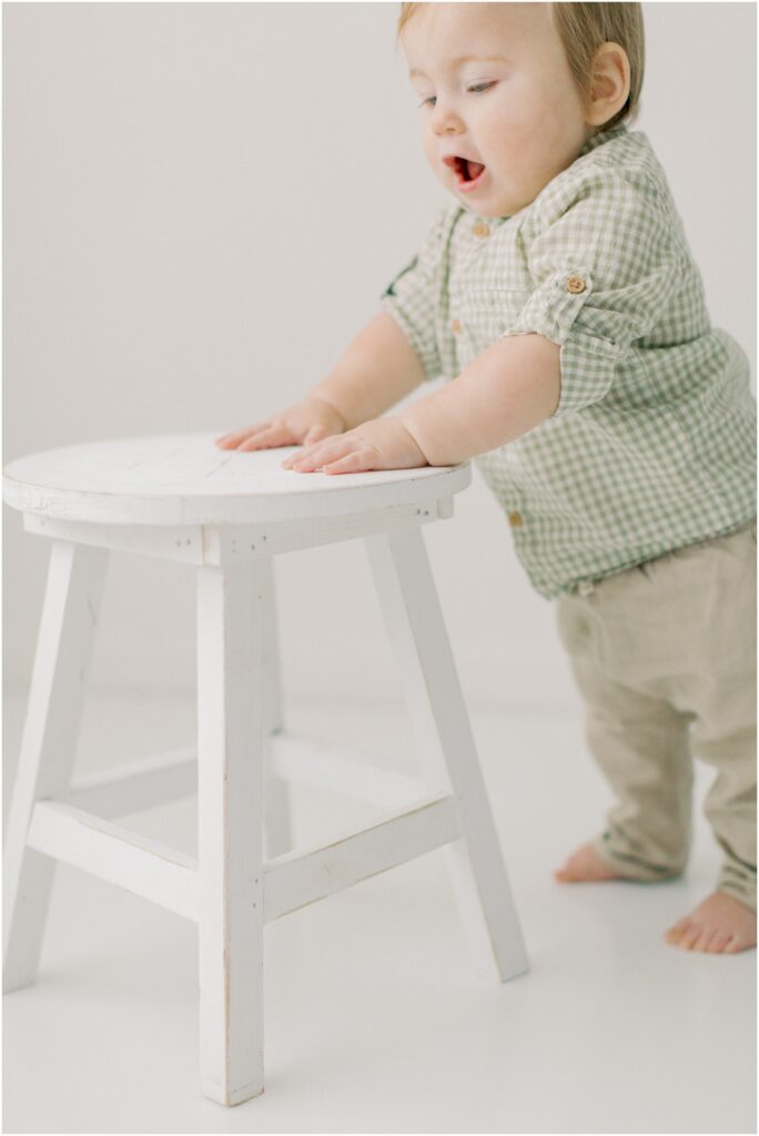Toddler's chubby hands on a stool at his first birthday session with Angelique Jasmin Photography