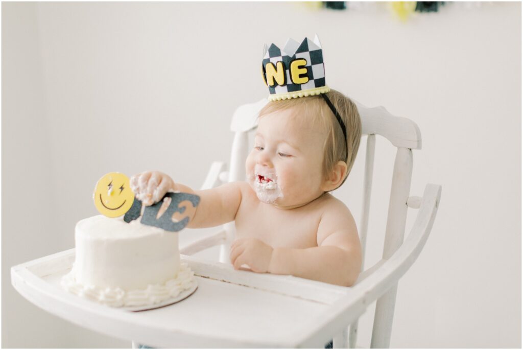 Toddler boy digging into his first birthday cake