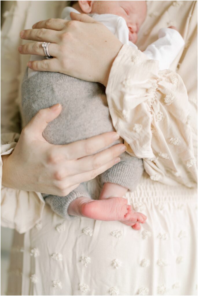 Details of newborn baby's feet in mother's hands