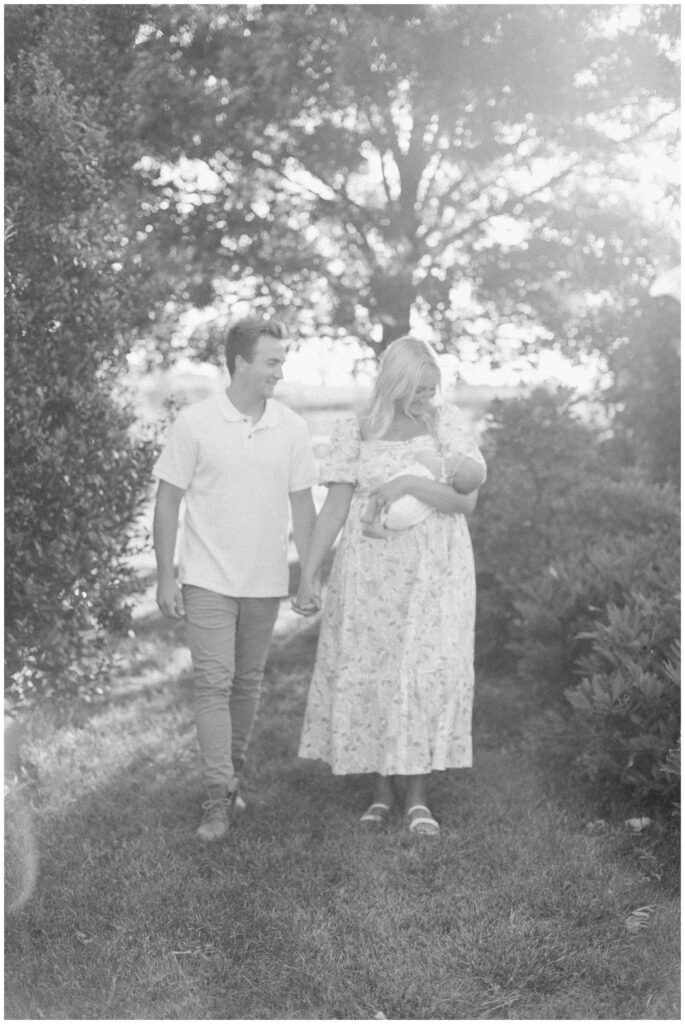 Black and white hazy image of new parents with their newborn in a flower garden