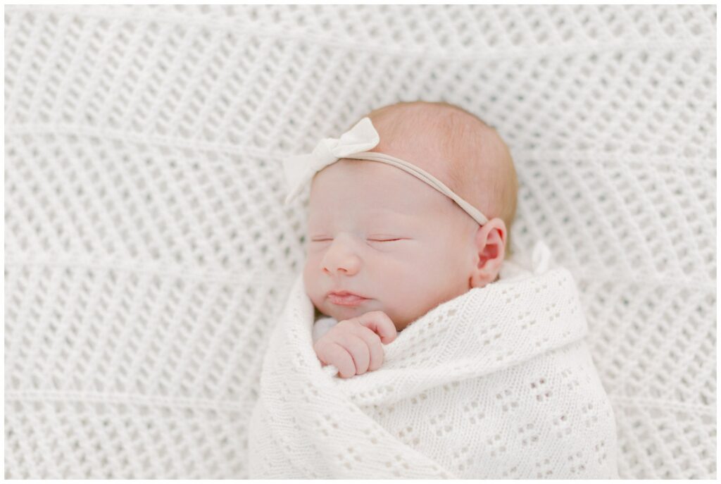 Newborn baby girl on a white crocheted blanket