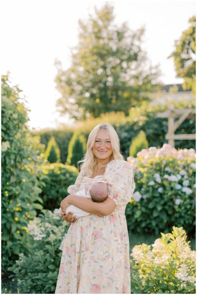Mother holding newborn baby girl in a Flower Garden Newborn Session in Lancaster, PA with Angelique Jasmin Photography